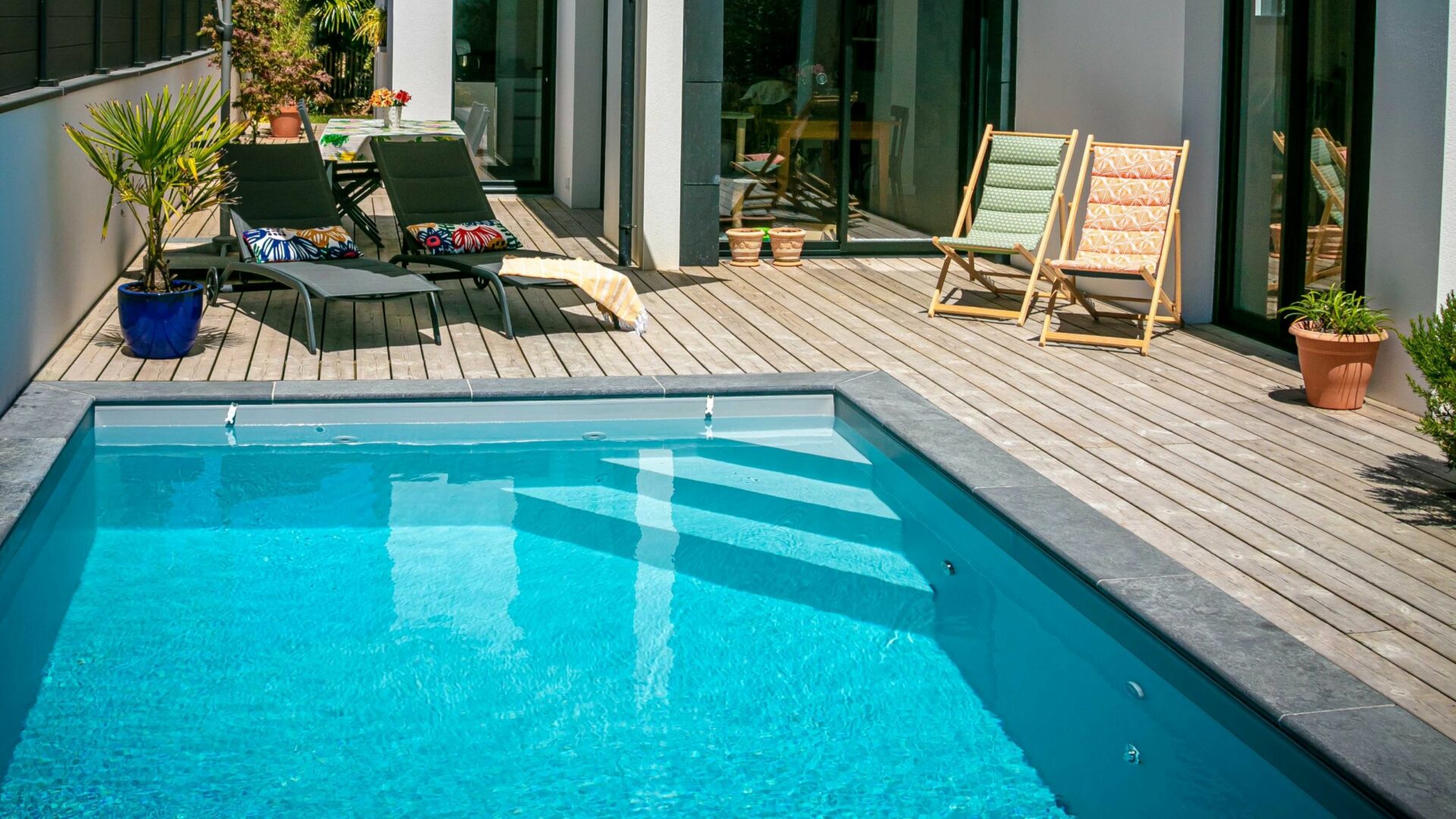Piscine au sel moderne avec terrasse en bois et transats, eau turquoise claire