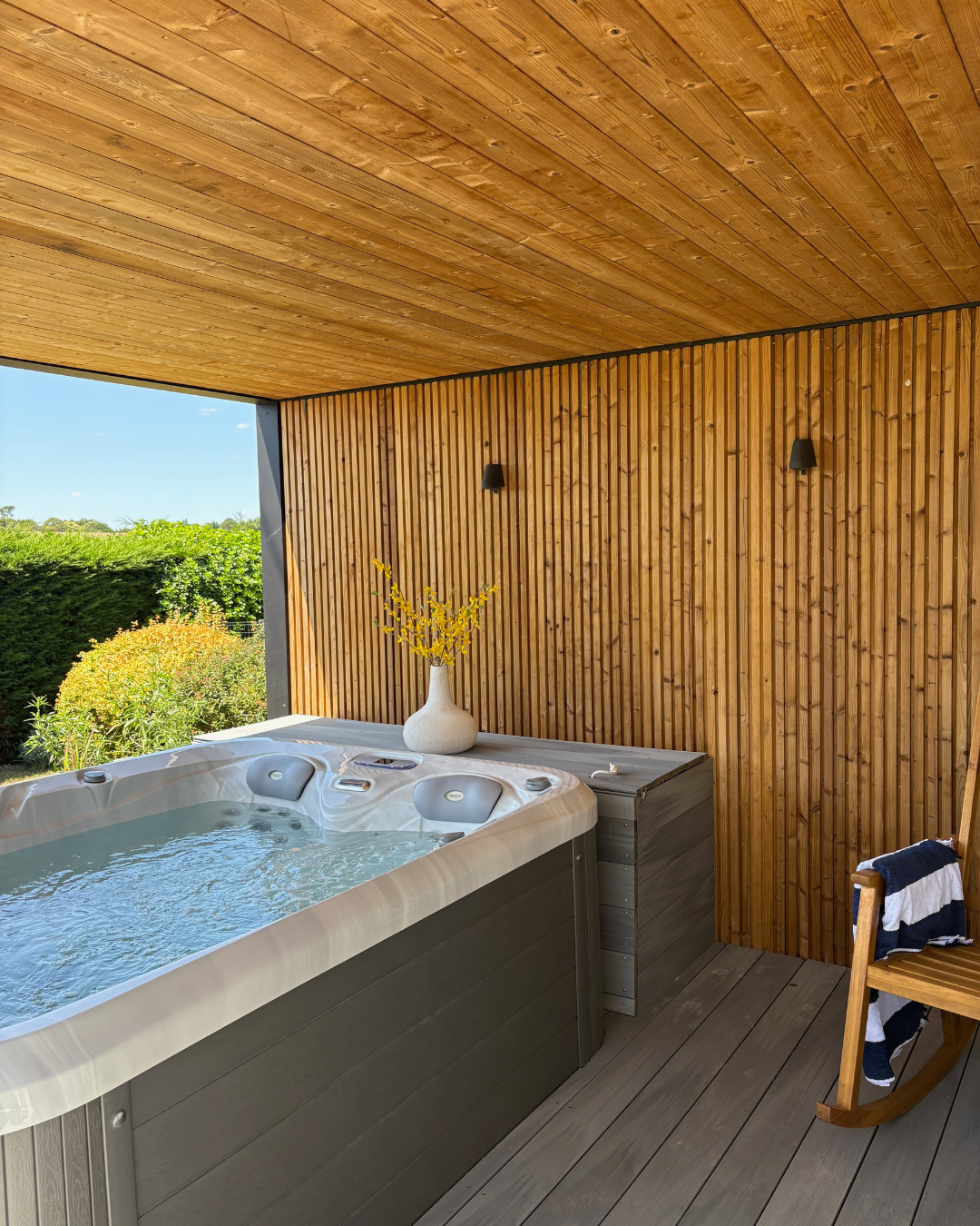 Spa extérieur sous pergola contemporaine en aluminium noir avec habillage bois et terrasse composite